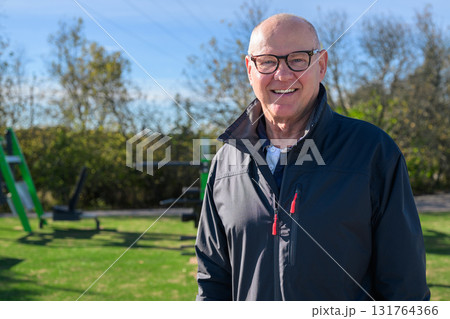Smiling senior man in sportswear exercising outdoors at park fitness area 131764366