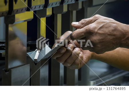 Close up the bending machine operator hold the sheet metal parts. 131764895