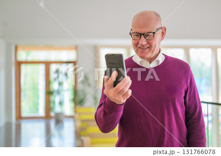 Portrait of senior man using mobile phone in living room at home 131766078