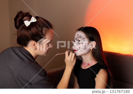 a makeup artist wears makeup for a young girl on Halloween. a makeup artist wears makeup for a young girl on Halloween. 131767180
