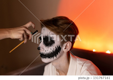 a young guy gets Halloween makeup as a scary skeleton. a young guy gets Halloween makeup as a scary skeleton. 131767181