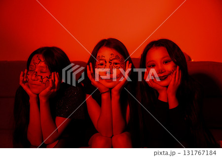 girls are sitting in room,with one of them holding a glowing carved pumpkin 131767184