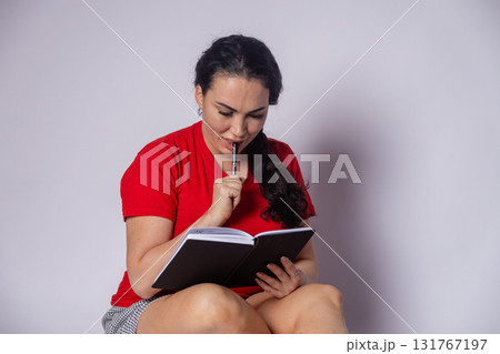 Woman seated on floor, absorbed in book Woman seated on floor, absorbed in book 131767197