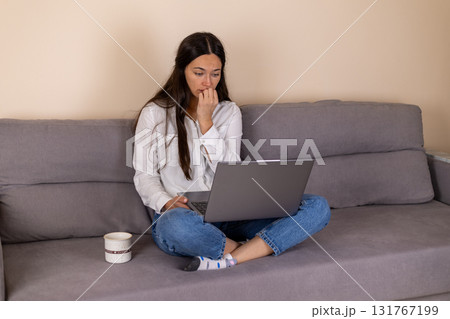 Woman sitting on couch with laptop, focused on screen. Woman sitting on couch with laptop, focused on screen. 131767199