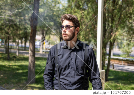 Man in sunglasses and black shirt walks confidently down city street 131767200