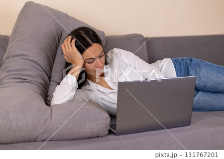 The woman is lying on a sofa and using a laptop The woman is lying on a sofa and using a laptop 131767201