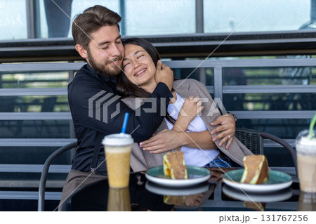 The man is hugging the woman while they are sitting at a table The man is hugging the woman while they are sitting at a table 131767256