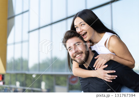 A man is giving a woman a piggyback ride while they both laugh and smile 131767394