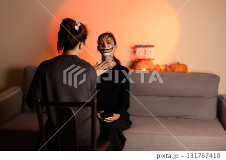a makeup artist wears makeup for a young girl on Halloween. a makeup artist wears makeup for a young girl on Halloween. 131767410