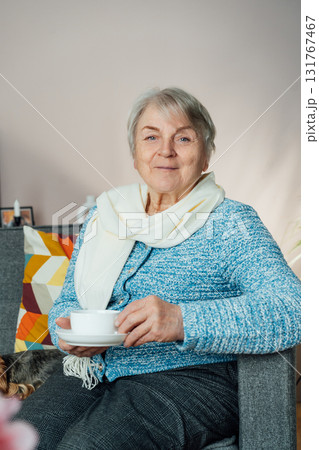 Smiling mature woman holding cup of tea, relaxing at home, positive senior female sitting on couch in modern living room looking satisfied feels good, older generation happy retired time enjoy life Smiling mature woman holding cup of tea, relaxing at home, positive senior female sitting on couch in modern living room looking satisfied feels good, older generation happy retired time enjoy life 131767467
