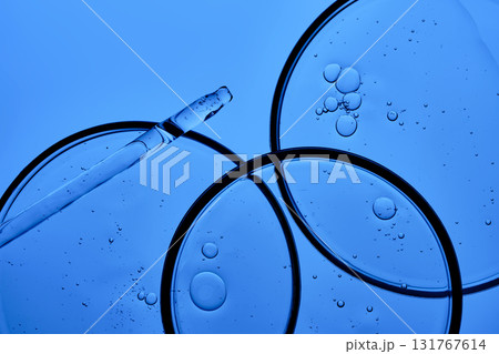 The texture of the serum with PDRN in a petri dish on a blue background. The texture of the serum with PDRN in a petri dish on a blue background. 131767614