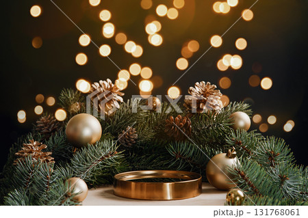Elegant holiday background with golden podium, pine branches, cones and baubles. Warm bokeh lights and copy space for luxury product display, banners and promos. 131768061
