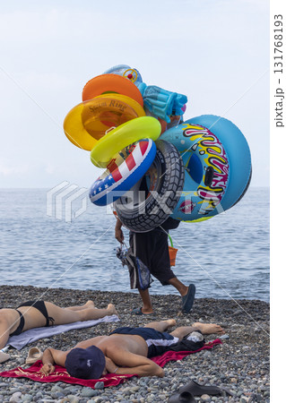 Title: 09.09.2025 - Batumi, Georgia -Swimming balloons seller on the beach. Travel Title: 09.09.2025 - Batumi, Georgia -Swimming balloons seller on the beach. Travel 131768193