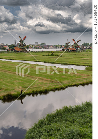 Scenic view of traditional Dutch windmills in Zaandam with changing skies, from calm daylight to approaching rain. 131768420