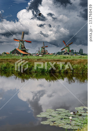 Scenic view of traditional Dutch windmills in Zaandam with changing skies, from calm daylight to approaching rain. Scenic view of traditional Dutch windmills in Zaandam with changing skies, from calm daylight to approaching rain. 131768439