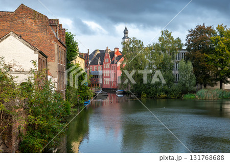 Serene cityscape of Ghent with still water reflecting old brick houses and charming streets. 131768688