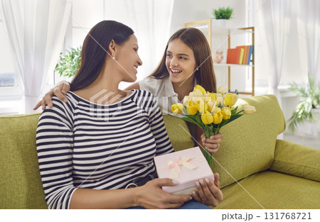 Little daughter gives present and bouquet of yellow tulips to her mom on Mother's Day Little daughter gives present and bouquet of yellow tulips to her mom on Mother's Day 131768721