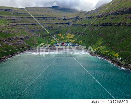 Scenic view of Tjornuvik, a charming village on the north coast of Streymoy, surrounded by dramatic mountains and ocean. 131768806
