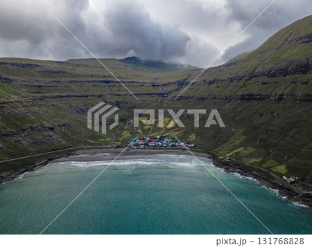 Scenic view of Tjornuvik, a charming village on the north coast of Streymoy, surrounded by dramatic mountains and ocean. Scenic view of Tjornuvik, a charming village on the north coast of Streymoy, surrounded by dramatic mountains and ocean. 131768828