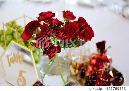 Red juicy roses against the background of a boiling white tablecloth. Banquet decoration. Wedding Red juicy roses against the background of a boiling white tablecloth. Banquet decoration. Wedding 131769358