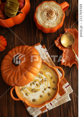 Autumnal lunch with pumpkin soup in a pumpkin-shaped bowl, pumpkin latte, croutons and festive decor on dark wooden table Autumnal lunch with pumpkin soup in a pumpkin-shaped bowl, pumpkin latte, croutons and festive decor on dark wooden table 131769389