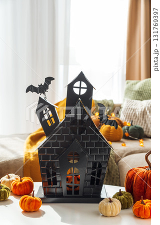 Halloween Decor with Pumpkins and Haunted House on Coffee Table near Cozy Couch Halloween Decor with Pumpkins and Haunted House on Coffee Table near Cozy Couch 131769397