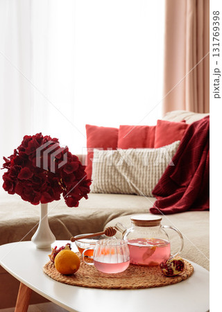 Glass Teapot and Teacup with Pomegranate Drink with Ginger and Citrus on Cozy Sofa with Autumn Decor Glass Teapot and Teacup with Pomegranate Drink with Ginger and Citrus on Cozy Sofa with Autumn Decor 131769398