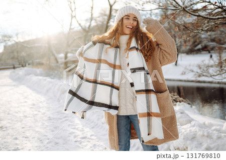 Portrait woman with mittens in a knitted hat and sheepskin coat outside in the city park in winter. Portrait woman with mittens in a knitted hat and sheepskin coat outside in the city park in winter. 131769810