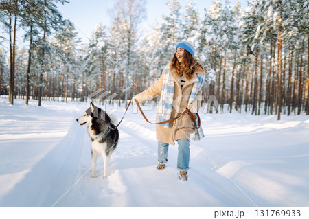 Woman laughing and playing with pet in the winter park. Husky dog. Domestic dog concept. Friendship. 131769933