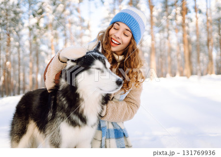 Woman laughing and playing with pet in the winter park. Husky dog. Domestic dog concept. Friendship. 131769936