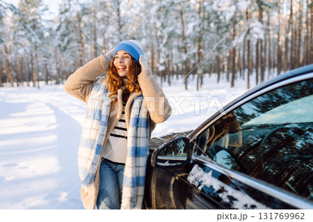 Beautiful woman is outdoors near automobile at winter time. Concept of car travel. Winter holidays. Beautiful woman is outdoors near automobile at winter time. Concept of car travel. Winter holidays. 131769962