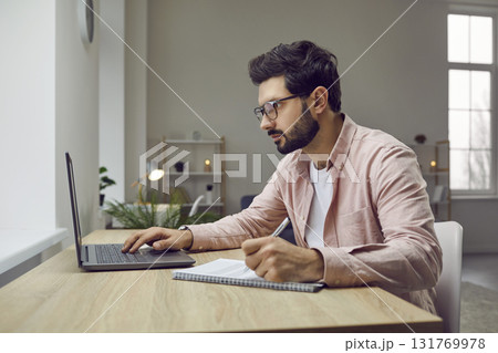 Side view shot of young man wearing glasses using laptop 131769978