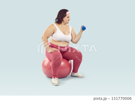 Fat woman doing fitness workout with sports equipment isolated on blue background 131770006