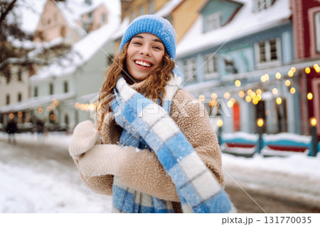 Happy woman in winter clothes walks on the street. Light all around. Winter holidays. 131770035