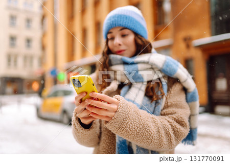 Phone in the hand of young woman in winter street. Online communication. Technology concept. Phone in the hand of young woman in winter street. Online communication. Technology concept. 131770091
