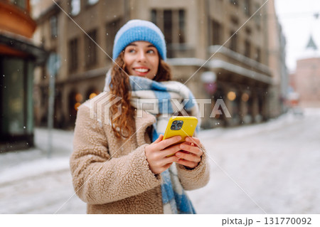 Phone in the hand of young woman in winter street. Online communication. Technology concept. Phone in the hand of young woman in winter street. Online communication. Technology concept. 131770092