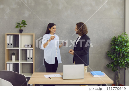 Two business people man and woman standing in office near the workplace and talking. Two business people man and woman standing in office near the workplace and talking. 131770649