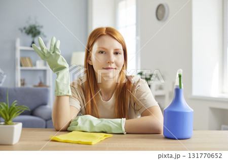 Young woman housewife with cleaning tools sitting at table at home and looking at camera. Young woman housewife with cleaning tools sitting at table at home and looking at camera. 131770652