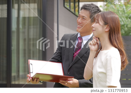 モデルハウスの案内をする営業スタッフと女性 131770953
