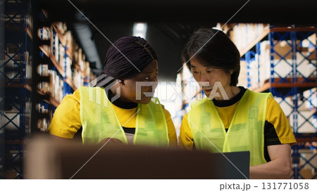 Diverse staff members organizing pallets on shelves and racks, processing orders in the industrial fulfillment center. Team handles distribution operations, managing inventory. Camera B. 131771058