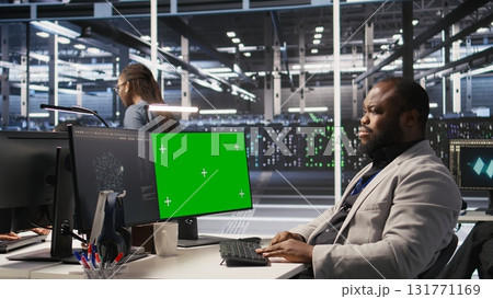 Data center programmer coding on green screen PC, monitoring AI systems. Server hub IT expert uses mockup computer to oversee rackmounts powering deep learning processes, camera A Data center programmer coding on green screen PC, monitoring AI systems. Server hub IT expert uses mockup computer to oversee rackmounts powering deep learning processes, camera A 131771169