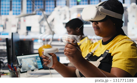 Photovoltaics factory employee monitors system performance using virtual reality gear. Solar panels manufacturing plant specialist employs VR headset to track energy production. Camera B. 131771189