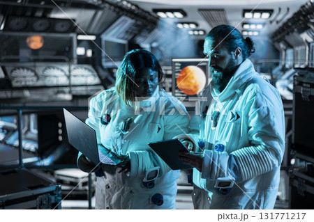 Astronauts in starship travelling to Mars navigating orbital trajectory using devices. Cosmonauts aboard orbit station ensuring operational readiness during cosmic journey to red planet 131771217