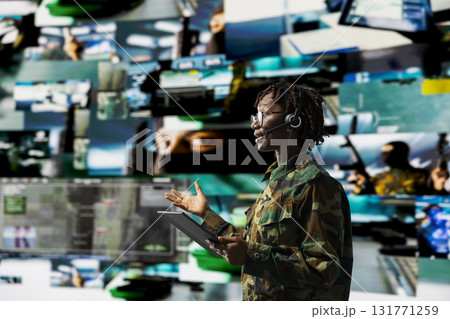 Army dispatcher wearing audio headset working in command center housing operational missile defense system designed to intercept rockets. African american woman tracking missiles using radar systems Army dispatcher wearing audio headset working in command center housing operational missile defense system designed to intercept rockets. African american woman tracking missiles using radar systems 131771259