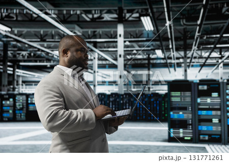Data center engineer using laptop to automate errors detection, minimizing downtime. Server hub IT expert monitoring components for potential failures, looking for network issues affecting rigs 131771261