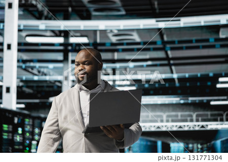Data center admin using laptop to automate errors detection, troubleshooting backend operations. Server hub IT expert monitoring components for potential failures, conducting regular security audits Data center admin using laptop to automate errors detection, troubleshooting backend operations. Server hub IT expert monitoring components for potential failures, conducting regular security audits 131771304