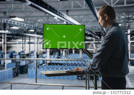 Server hub IT expert uses mockup chroma key computer, implementing efficiency optimizations. Data center admin using green screen PC monitor, implementing efficiency optimizations in across rigs 131771312