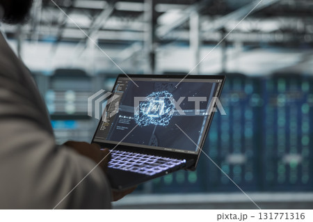 Close up of engineer using laptop in data center housing advanced equipment used for complex AI calculations. Server room IT professional running artificial intelligence code to optimize performance Close up of engineer using laptop in data center housing advanced equipment used for complex AI calculations. Server room IT professional running artificial intelligence code to optimize performance 131771316