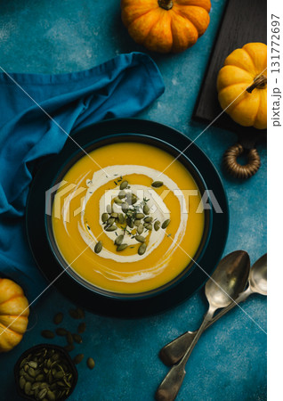 Pumpkin soup in a blue bowl, blue background. Autumn food, top view Pumpkin soup in a blue bowl, blue background. Autumn food, top view 131772697