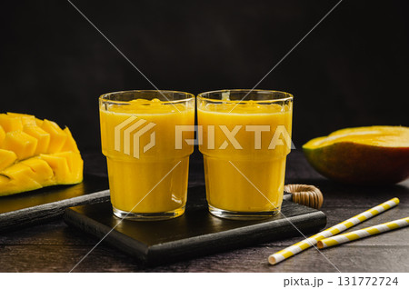 Mango banana smoothie in a glass with fresh fruit, black background 131772724